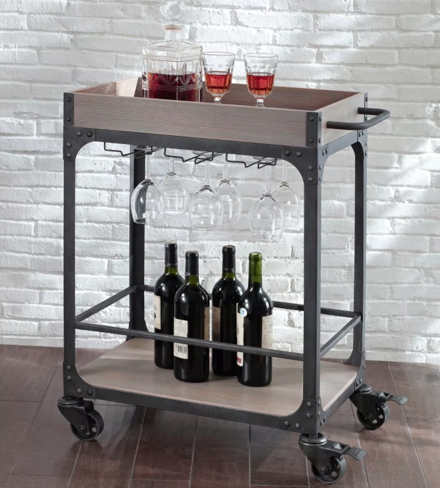 the bar cart with wine glasses and liquor on top 