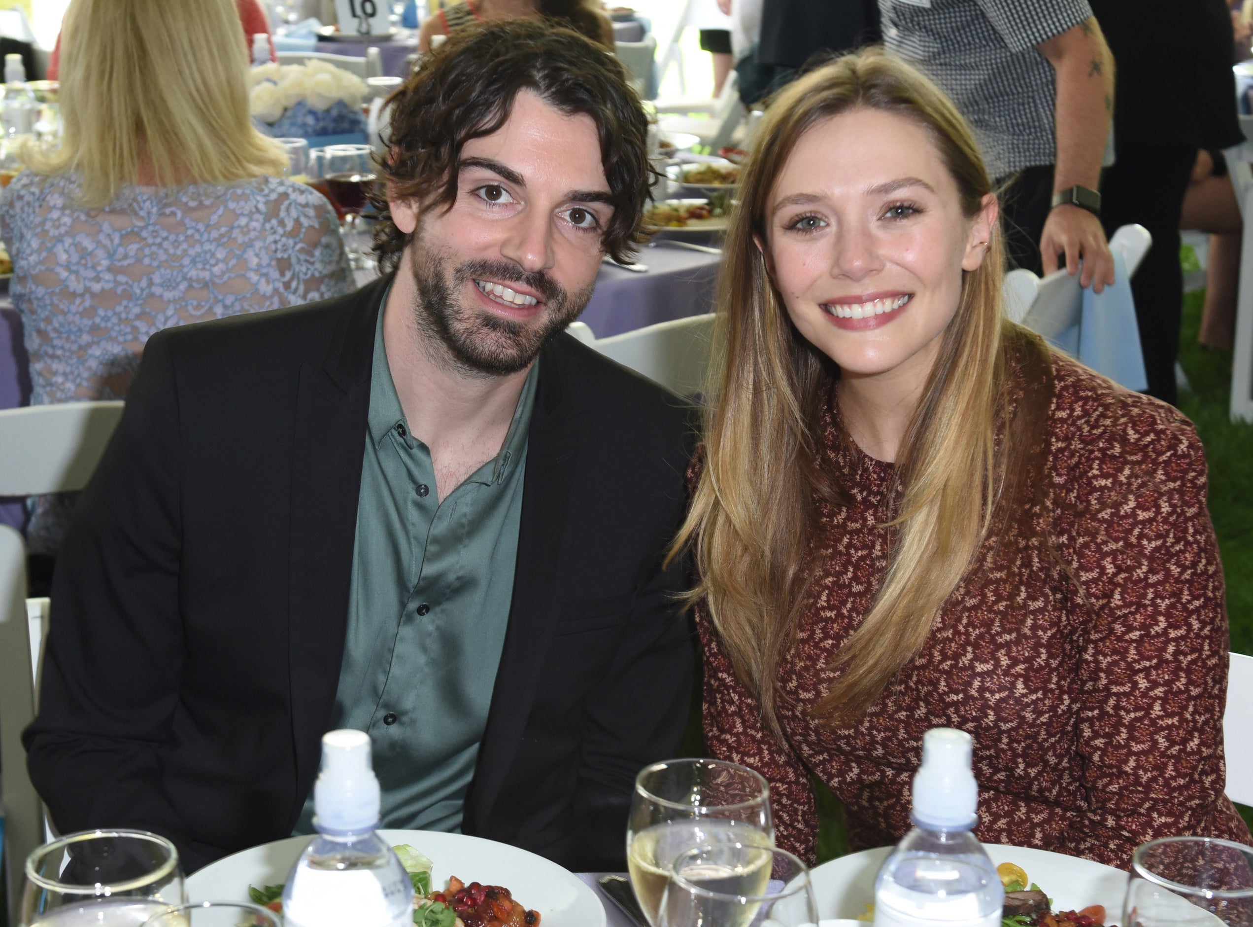 Elizabeth and Robbie sit next to each other at a dining table