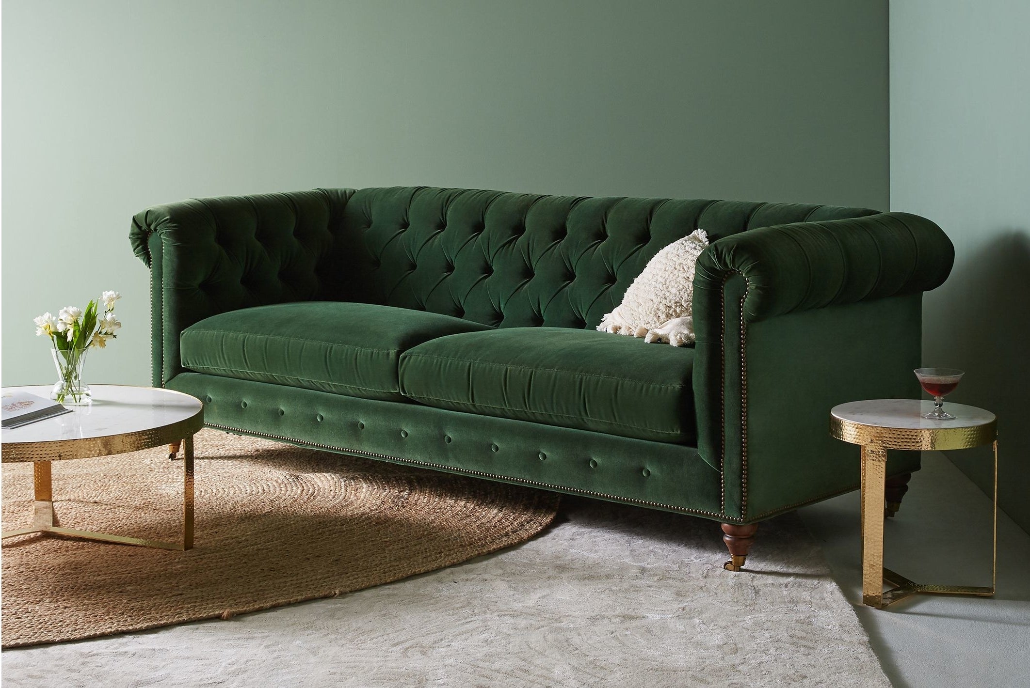 A display of the green velvet sofa with a coffee table and end table in the frame