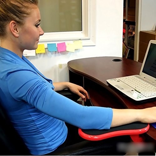 Woman sitting at her work desk with the armrest supporting her hand.