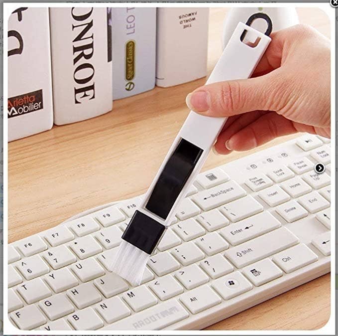 Mini cleaning brush being used to clean laptop keys