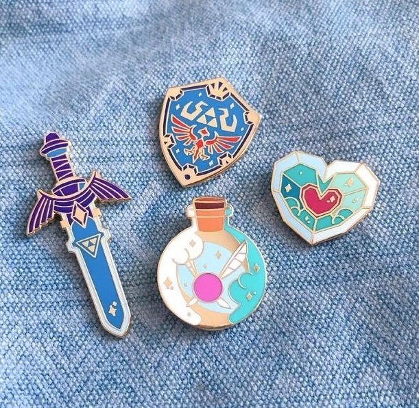 four legend of zelda pins: master sword, hyleian shield, fairy bottle, and heart piece