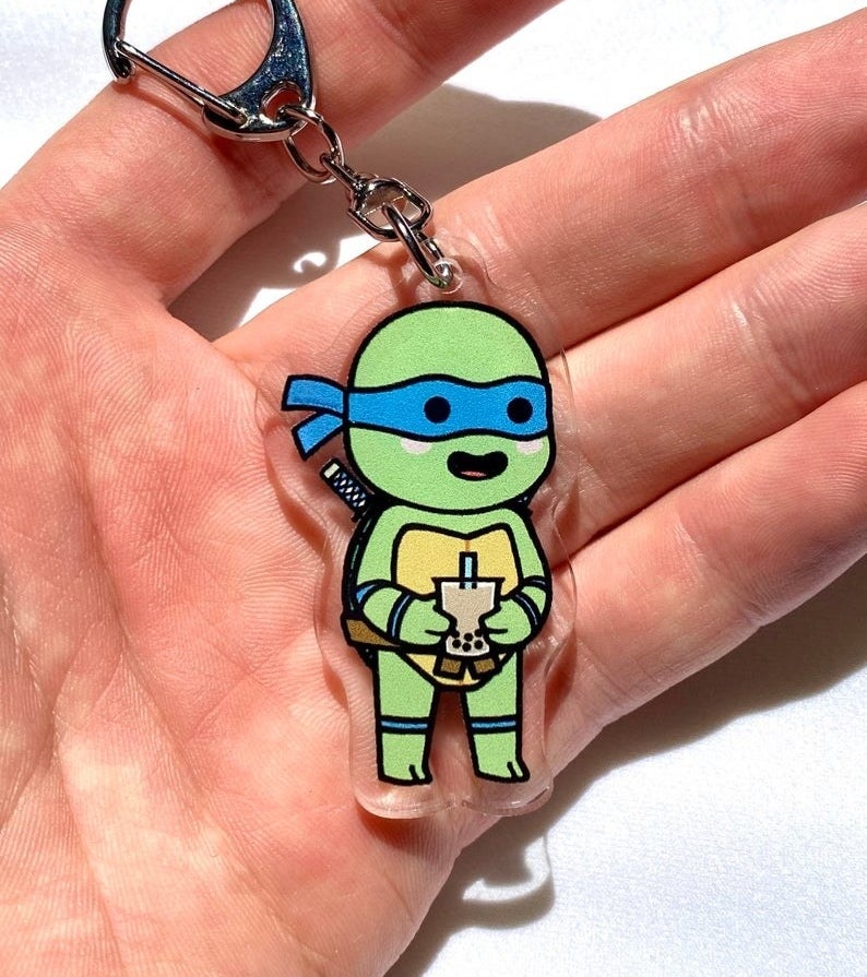 a little ninja turtle on a keychain holding a cup of bubble tea