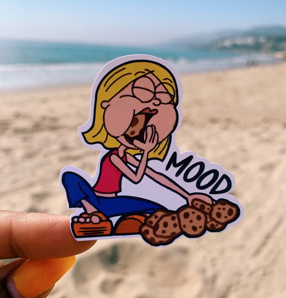 A sticker of the Lizzie Mcguire cartoon persona eating cookies next to the word &quot;mood&quot;