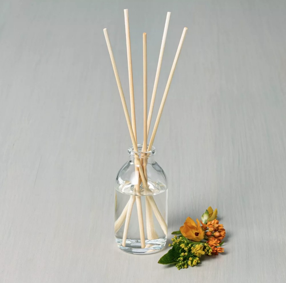 A 3 fl oz Golden Hour Seasonal Oil Diffuser displayed next to a small bouquet of flowers