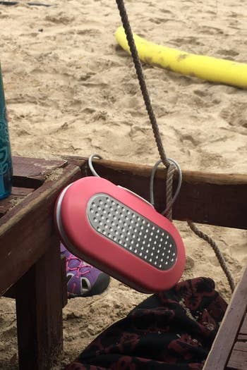 reviewer's pink personal safe that's attached to a beach chair at the beach