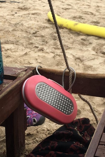 reviewer photo of a pink personal safe that's attached to a beach chair at the beach