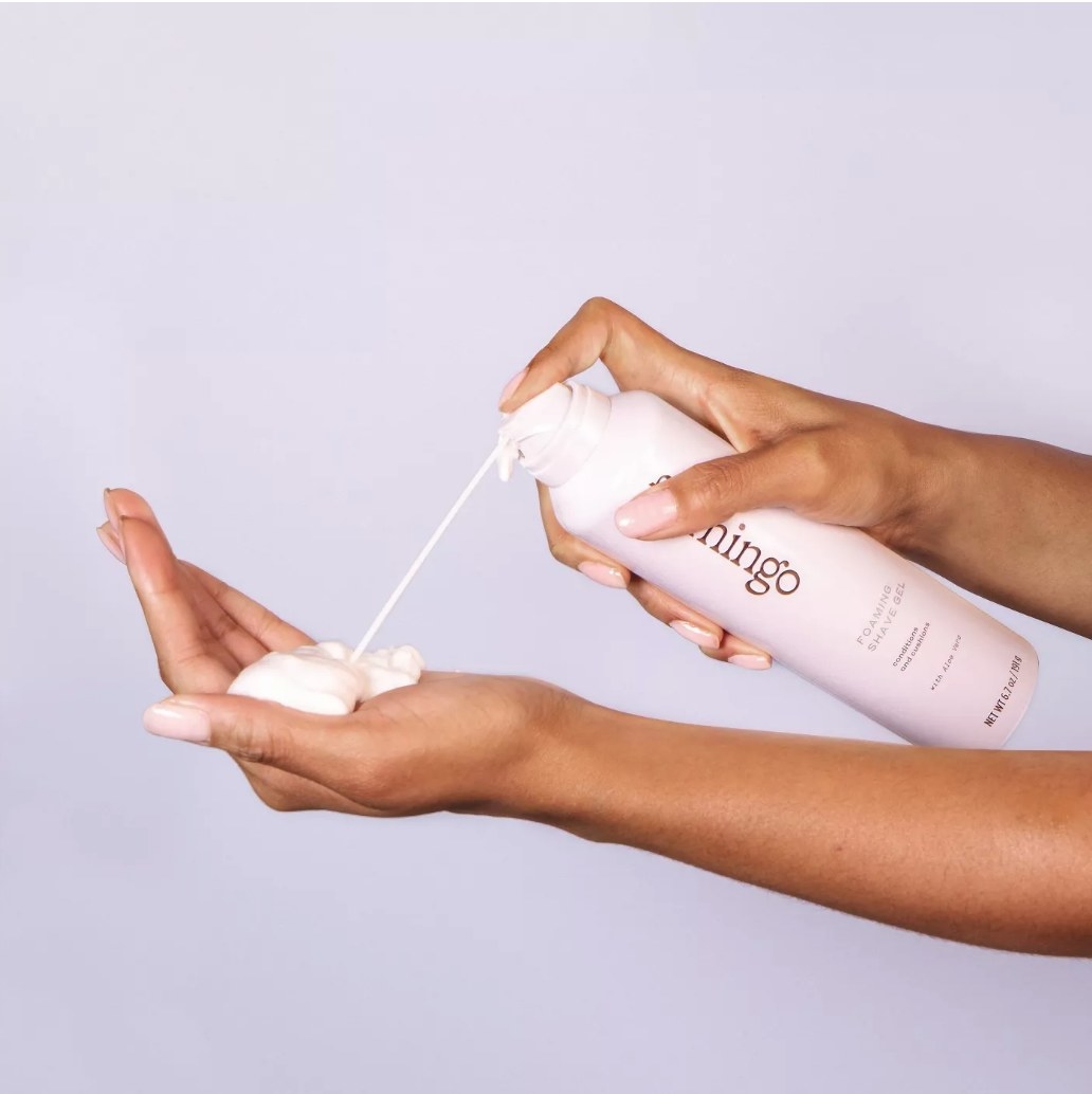 a model spraying foam into their hand from a bottle of Flamingo Women&#x27;s Foaming Shave Gel