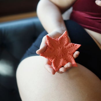 Model holding orange star-shaped vibrator curved in palm