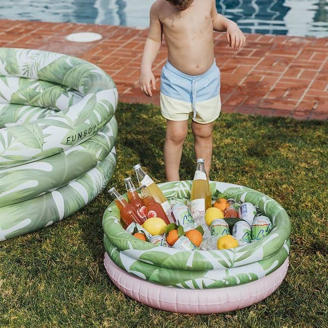 kiddie pool-shaped tropical print cooler with bottles and cans in it