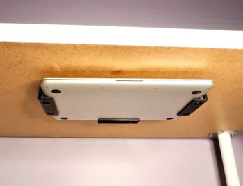 Laptop placed in brackets under desk