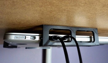 Side of laptop bracket with chargers placed through
