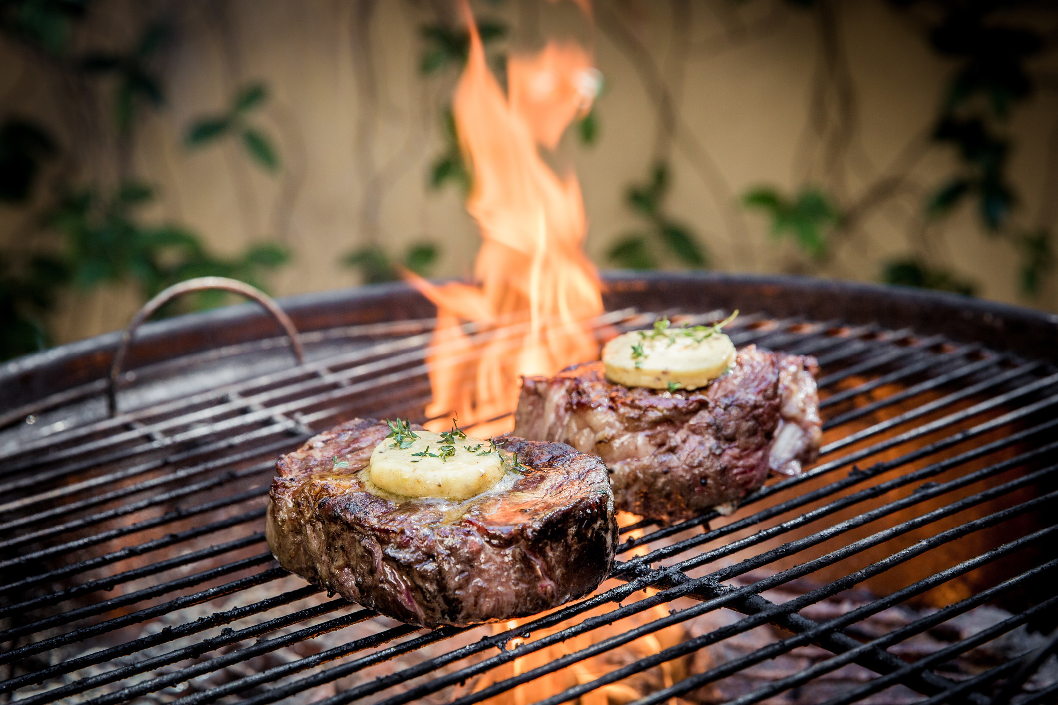 Two steaks cooking on a flame.