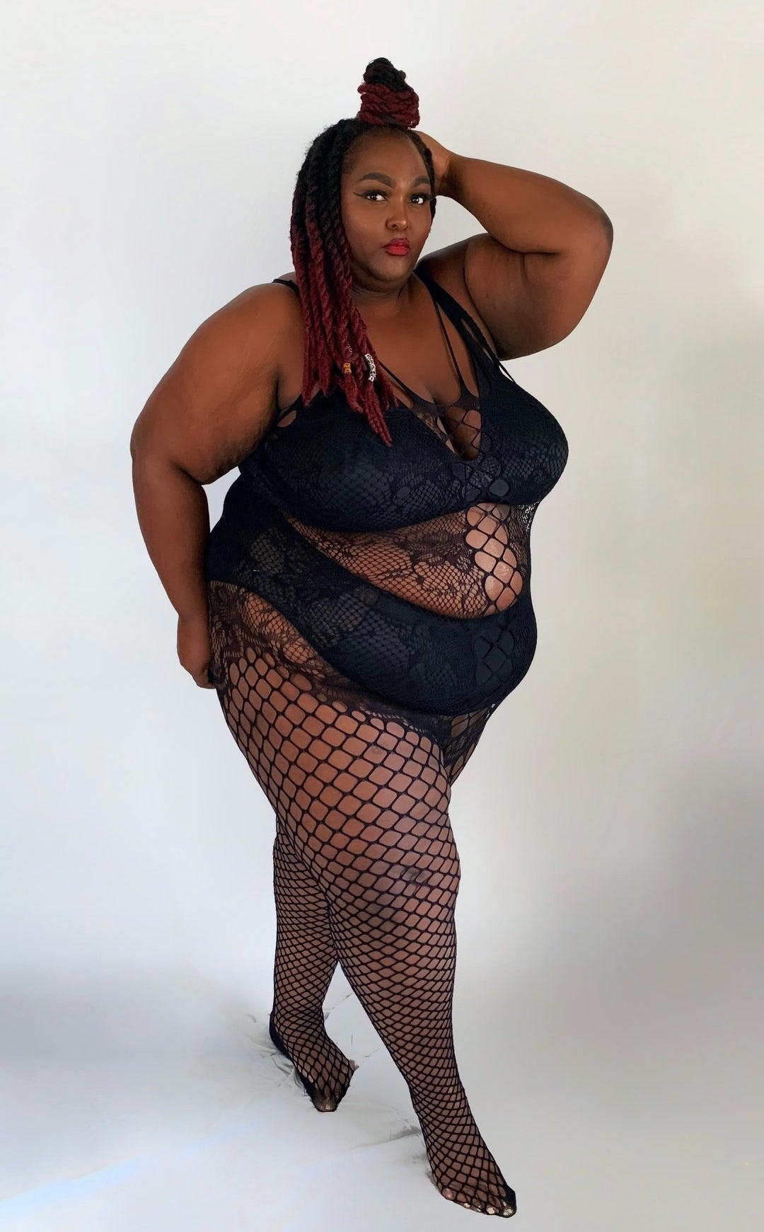 a plus size model wearing the all-in-one fishnet body stocking
