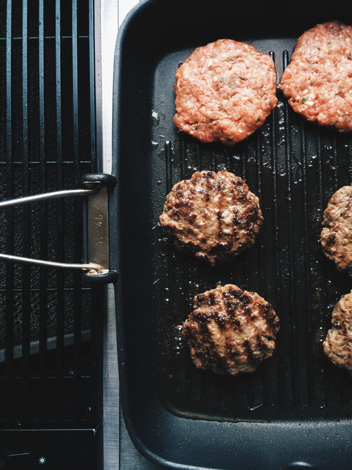 Burger patties cooking on a grill.