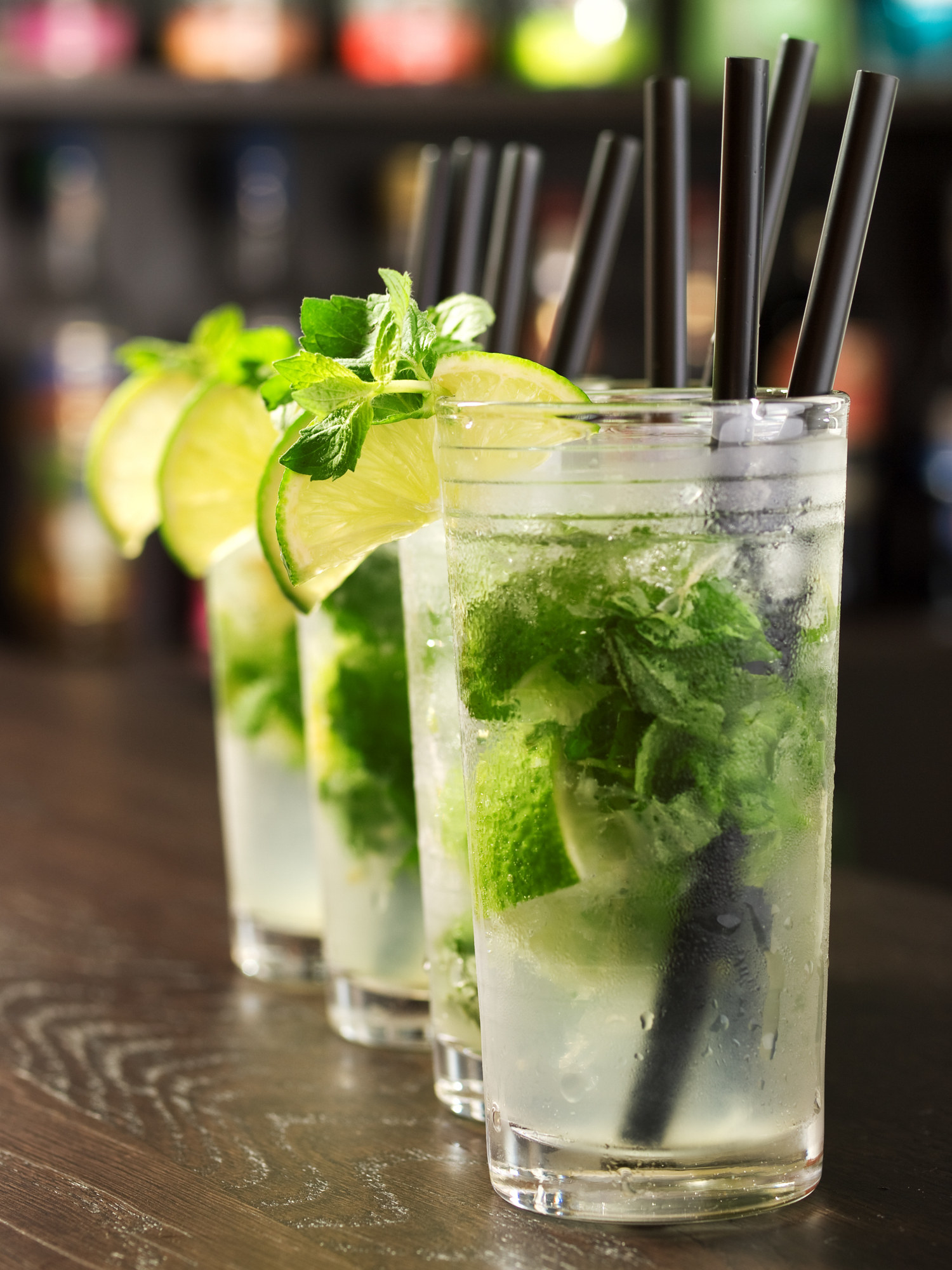 A line of Mojito drinks resting on a bar