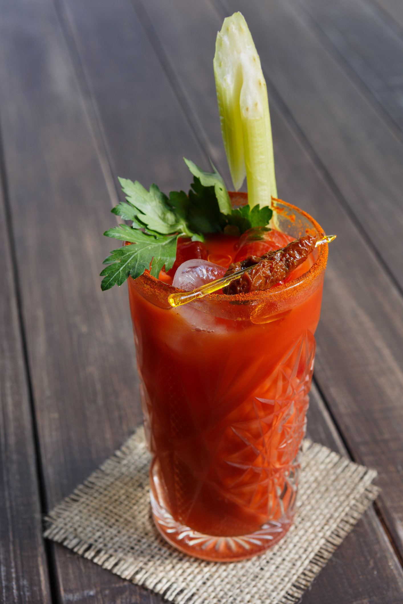 A glass of bloody mary with garnishes and a pepper