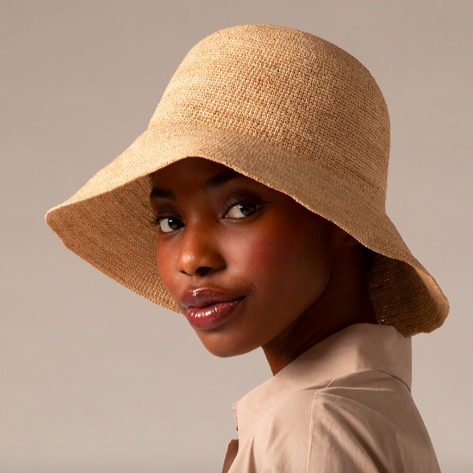 A person wearing a floppy oversized straw bucket hat