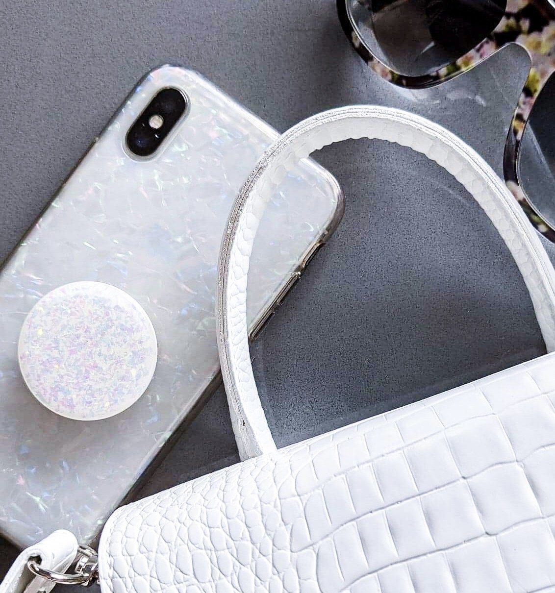 A flatlay of the opal phone case peeking out of a matching handbag