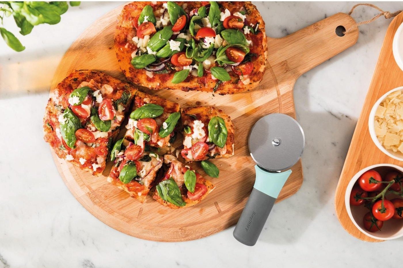 pizza and a pizza cutter on a bamboo board 