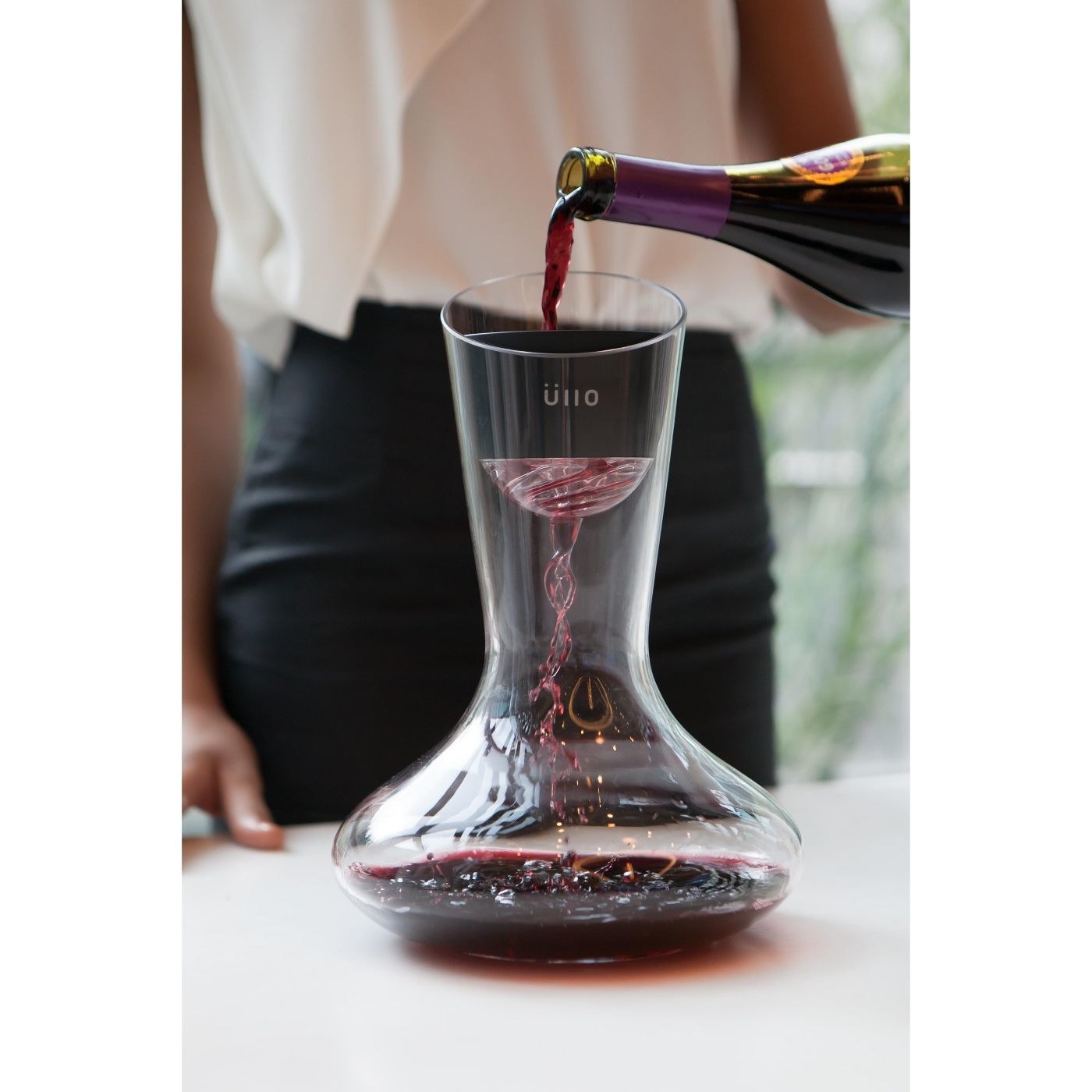 wine being poured through an aerator into a decanter 
