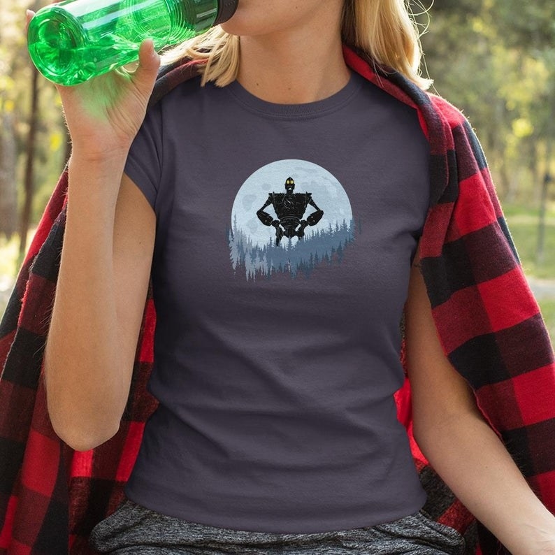 A person wearing a t-shirt with the iron giant in a forest designed on the front