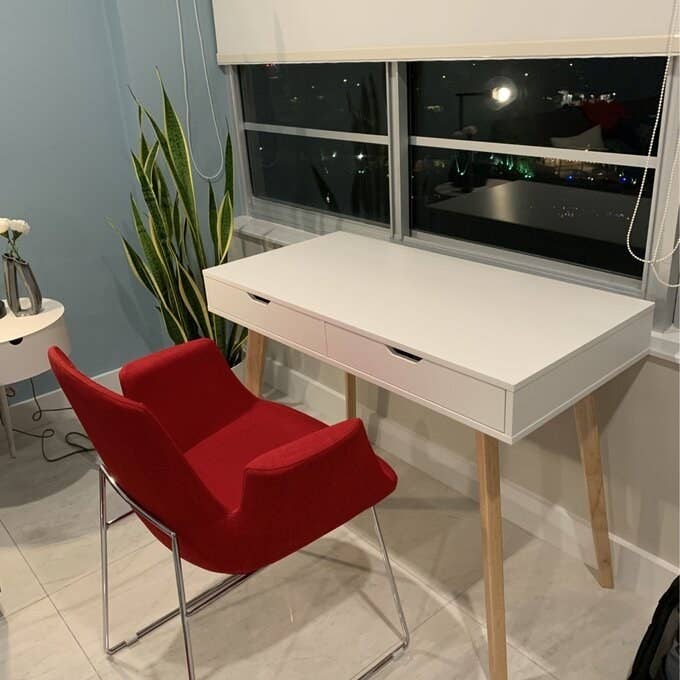 The white desk with natural wood legs in a reviewer's room