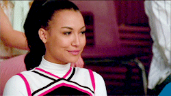 Santana Lopez smirks before moving her eyebrows up and down in a flirty gesture.