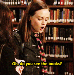 GIF of rory from gilmore girls in a library saying &quot;oh, do you see the books?&quot; to someone