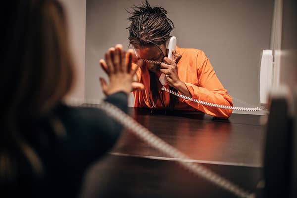 A prisoner talking to a visitor through glass