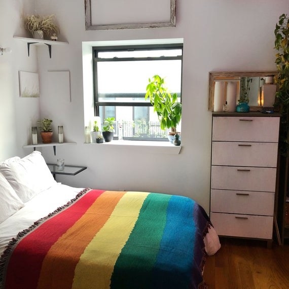 Rainbow rectangle quilt on bed with white sheets