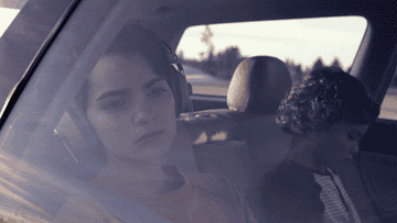 GIF of elodie from trinkets looking out of a car window