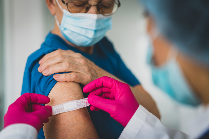 Doctor makes vaccination to senior woman with surgical mask