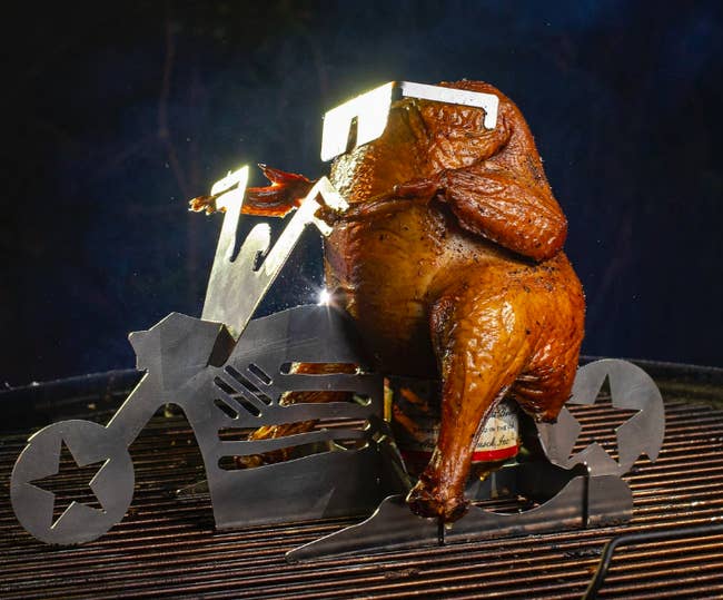 Roasted chicken being grilled with a beer and chicken stand that looks like a motorcycle 
