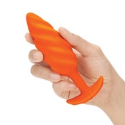 Model holding medium orange butt plug with swirl texture