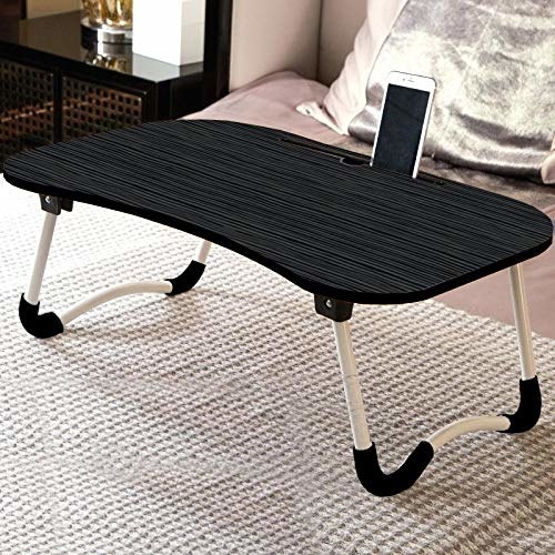 A laptop desk on a bed with a phone on it