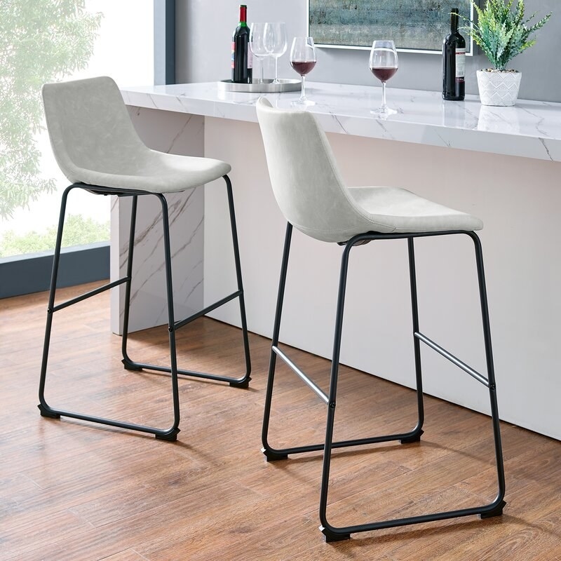 grey faux leather bar stools with black legs next to a counter