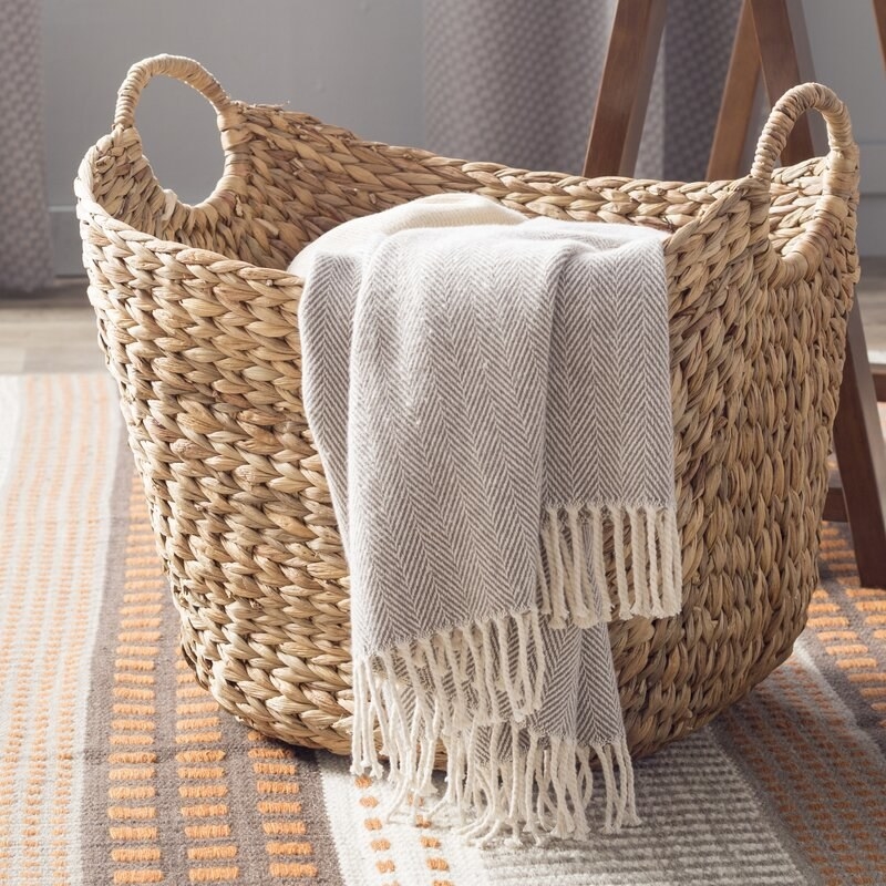 wicker basket with handles and a blanket inside