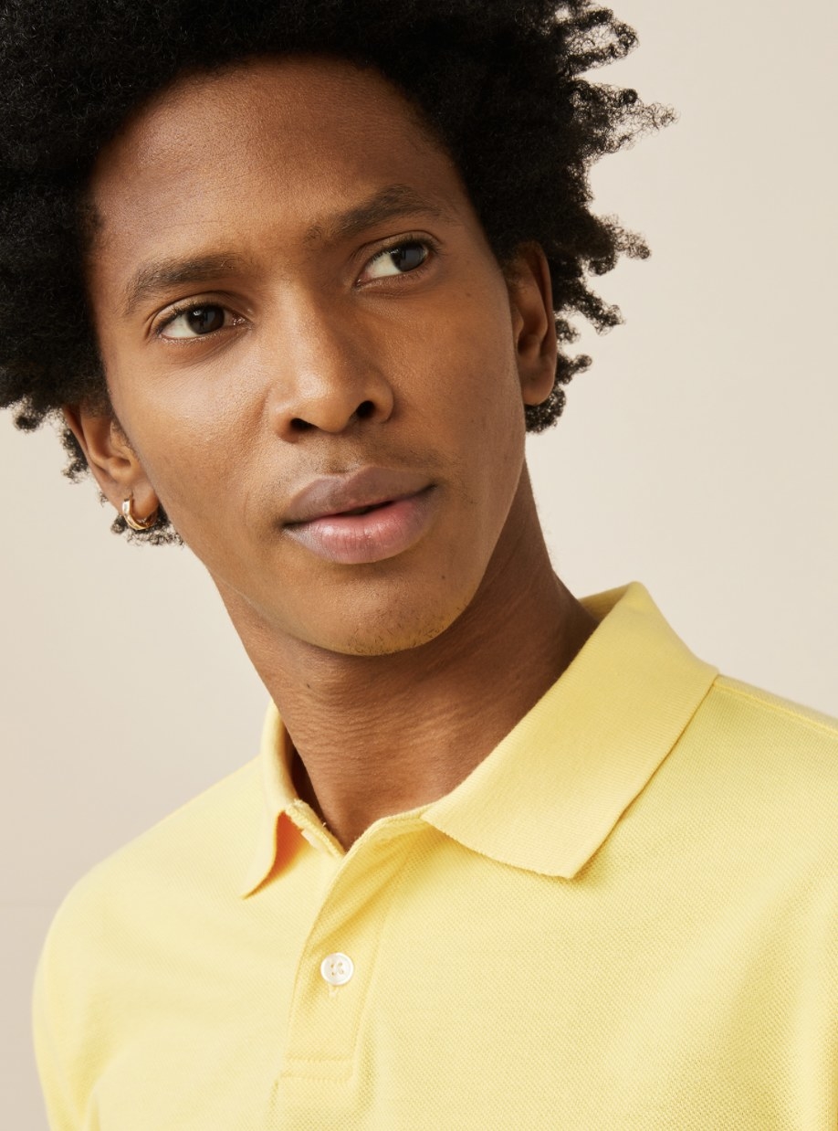An adult gazes off the screen in the laguna yellow polo
