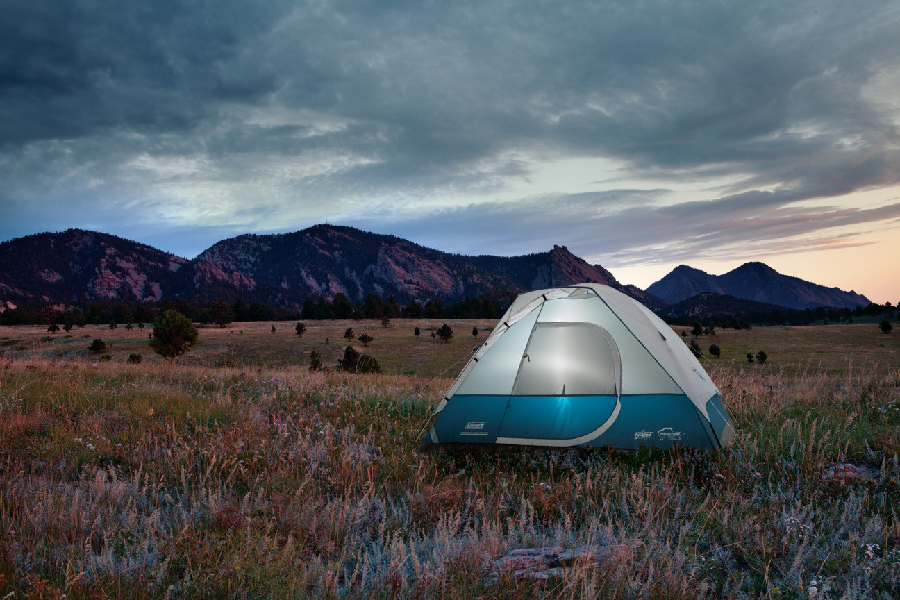 Coleman tent in the middle of a field with mountains in the background