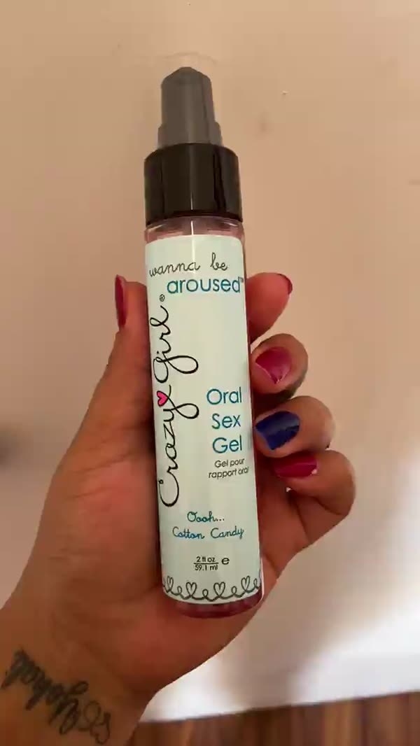 Reviewer holding spray bottle of Crazy Girl cotton candy oral sex gel and lubricant