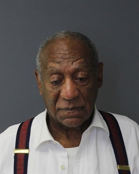 Bill Cosby wearing suspenders and looking down