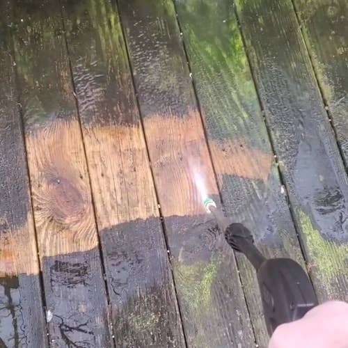 reviewer using an electric power washer to clean a deck