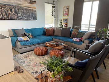 reviewer photograph of an extra-long sectional sofa with bluish sofa cover