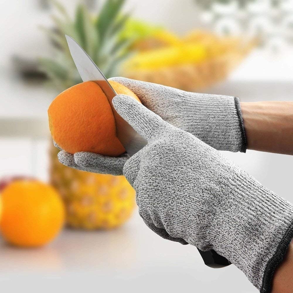 A person wearing the cut-resistant gloves while cutting a fruit.