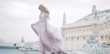 Taylor Swift walking around in a flowy purple dress