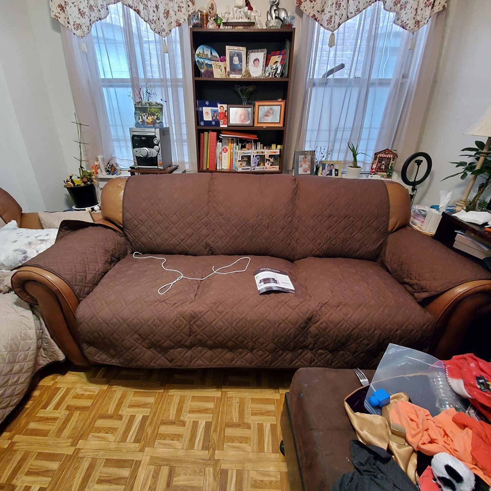 reviewer photo of the brown sofa cover over a light brown leather couch