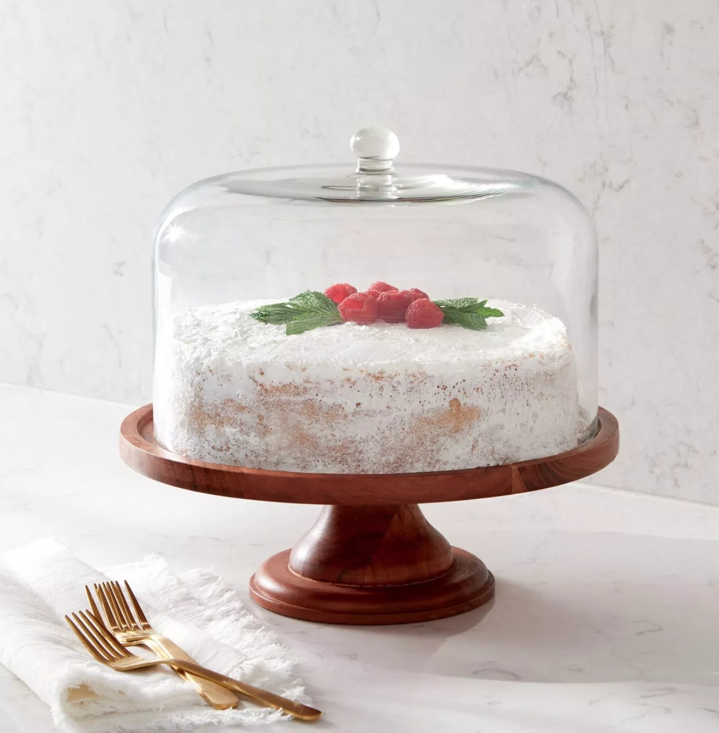the wooden stand with a cake inside and glass covering on top