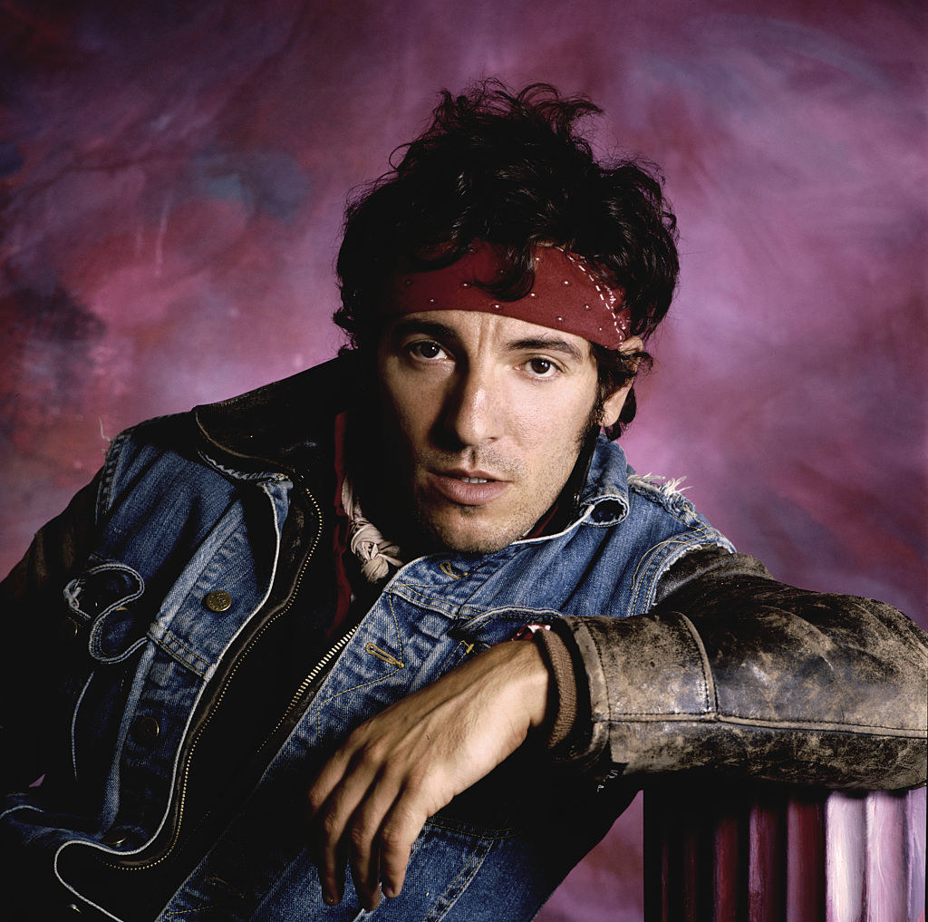 Bruce Springsteen posing for a portrait in a bandana and denim vest in the mid-&#x27;80s