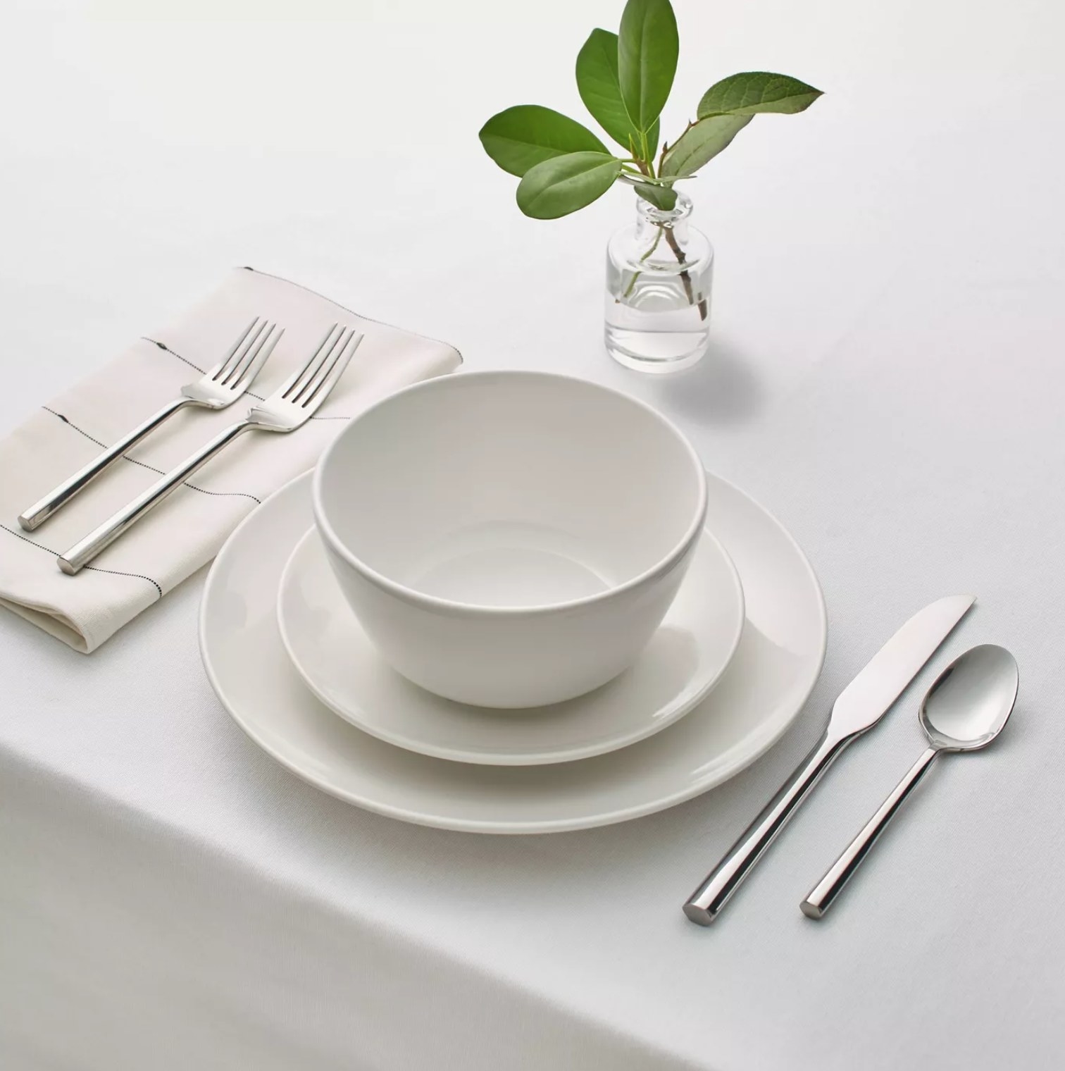 one dinner plate, one salad, plate and one bowl on a table with silverware
